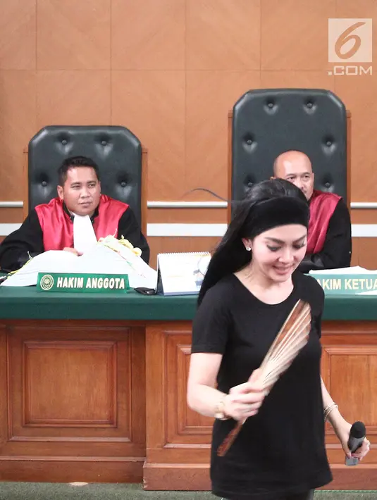 Penyanyi Syahrini bersaksi sambil memegang kipas pada sidang kasus First Travel di Pengadilan Negeri Depok, Jawa Barat, Senin (2/4). Saat memberikan kesaksian, Syahrini merasa kepanasan sehingga kipas-kipas dan membuka jaket (Liputan6.com/Herman Zakharia)