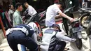 Petugas mengempeskan ban motor saat melakukan penertiban di kawasan pusat perbelanjaan Pasar Baru, Jakarta, Rabu (21/2). Penertiban dilakukan dengan membongkar lapak PKL serta kendaraan yang parkir di trotoar. (Liputan6.com/Immanuel Antonius)
