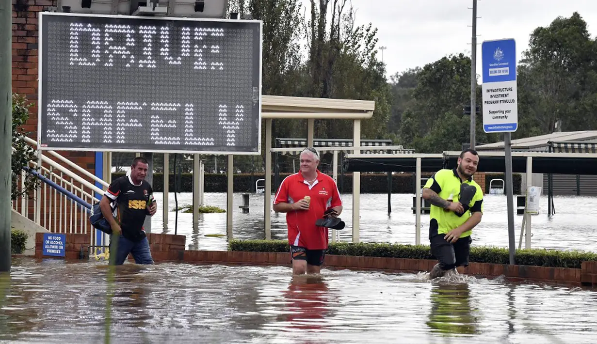 Warga mengarungi banjir yang meningkat di pinggiran barat daya Camden, Sydney, Australia, Selasa (8/3/2022). (Muhammad FAROOQ/AFP)