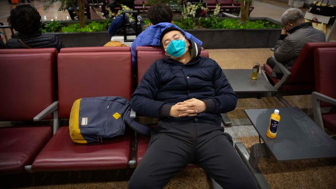 Pelancong memakai masker saat tidur siang di Bandara Internasional Ibu Kota Beijing, 23 Januari 2020. China pada Kamis (23/1) menutup sebuah kota berpenduduk lebih dari 11 juta orang dalam upaya memerangi wabah virus corona, tindakan yang belum pernah terjadi sebelumnya.  (AP/Mark Schiefelbein)