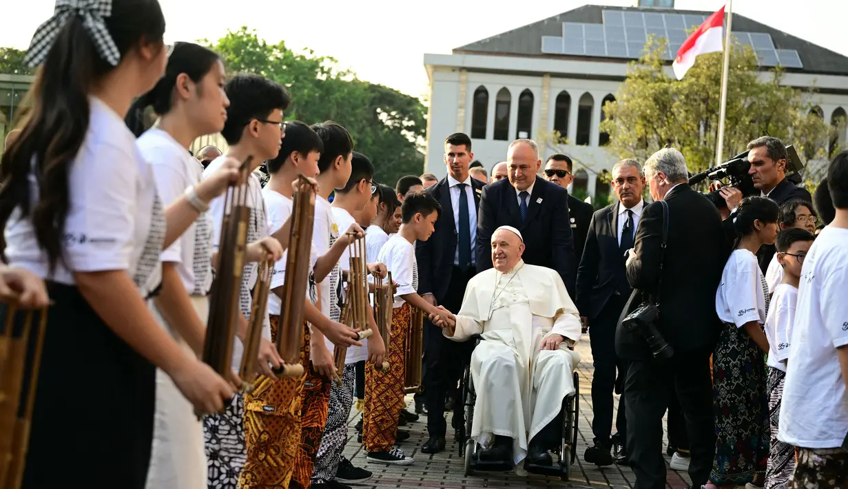 Kedatangan Paus Fransiskus disambut sejumlah pelajar dengan memainkan alat musik, angklung. (Tiziana FABI/AFP)