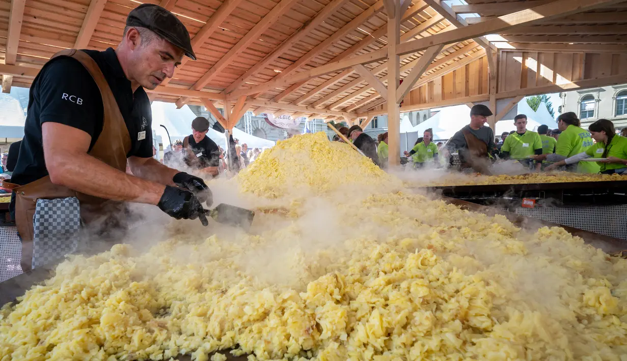 Koki memasak rosti dalam upaya memecahkan rekor dunia saat acara yang menandai peringatan 125 tahun Serikat Petani Swiss (SBV) di Bern, Swiss pada 19 September 2022. Rosti atau roschti adalah makanan khas Swiss berbahan dasar kentang yang dihaluskan dan digoreng menggunakan sedikit minyak. (Fabrice COFFRINI / AFP)