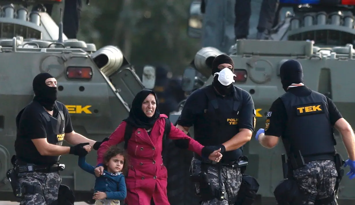 Polisi anti huru-hara mengevakuasi imigran wanita dan anaknya dari bentrokan yang terjadi antara polisi dengan imigran yang berusaha menerobos pintu perbatasan Serbia dan Hungaria di Roszke, Rabu (16/9/2015). (REUTERS/Dado Ruvic)