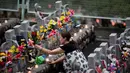 Seorang wanita menaruh bunga di depan patung Jizo yang didedikasikan untuk jiwa anak-anak yang telah meninggal dunia di Kuil Buddha Jizoji, Oganomachi, Prefektur Saitama, Jepang, Senin (13/8). (Behrouz Mehri/AFP)