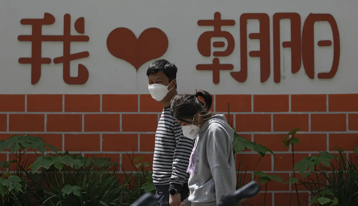 <p>Pejalan kaki yang mengenakan masker berjalan di dekat dinding yang memajang tulisan "I Love Chaoyang" saat akan menjalani tes COVID-19 di distrik Chaoyang, Beijing, Rabu (11/5/2022). Shanghai pada Rabu menegaskan kembali akan mempertahankan pendekatan &ldquo;nol-COVID&rdquo; pengendalian pandemi, sehari setelah kepala Organisasi Kesehatan Dunia (WHO) menyatakan kebijakan itu tidak berkelanjutan dan mendesak China mengubah strategi. (AP Photo/Andy Wong)</p>