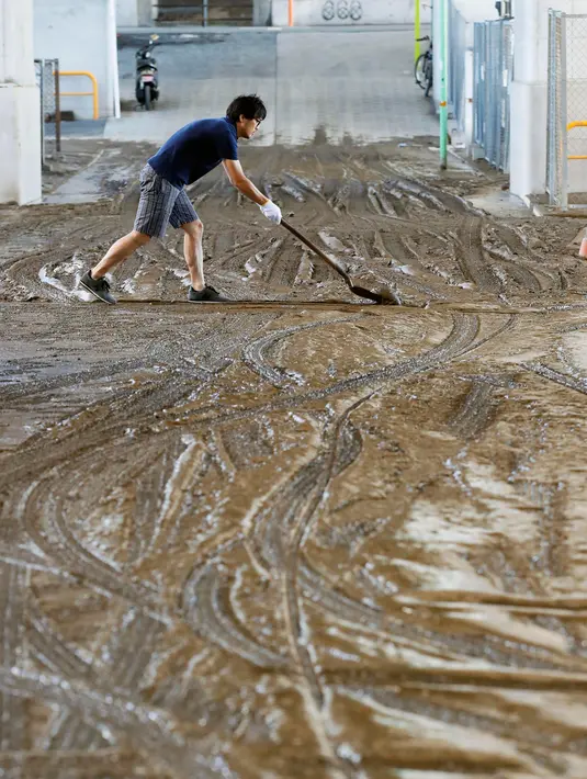 Seorang pria membersihkan lumpur  sisa banjir setelah topan Hagibis melanda Tokyo, Minggu (13/10/2019).  Topan Hagibis di Jepang akhir pekan ini  disebut sebagai badai terburuk sejak 60 tahun terakhir yang pernah melanda Negeri Sakura. (Kyodo News via AP)