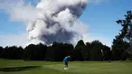 Doug Ralston bermain golf saat kepulan asap abu vulkanik berembus dari puncak gunung Kiluaea di Volcano, Hawaii (21/5). Lava dari gunung Kilauea Hawaii mengalir ke laut dan memicu reaksi kimia yang menciptakan asap hitam. (AP Photo/Jae C. Hong)