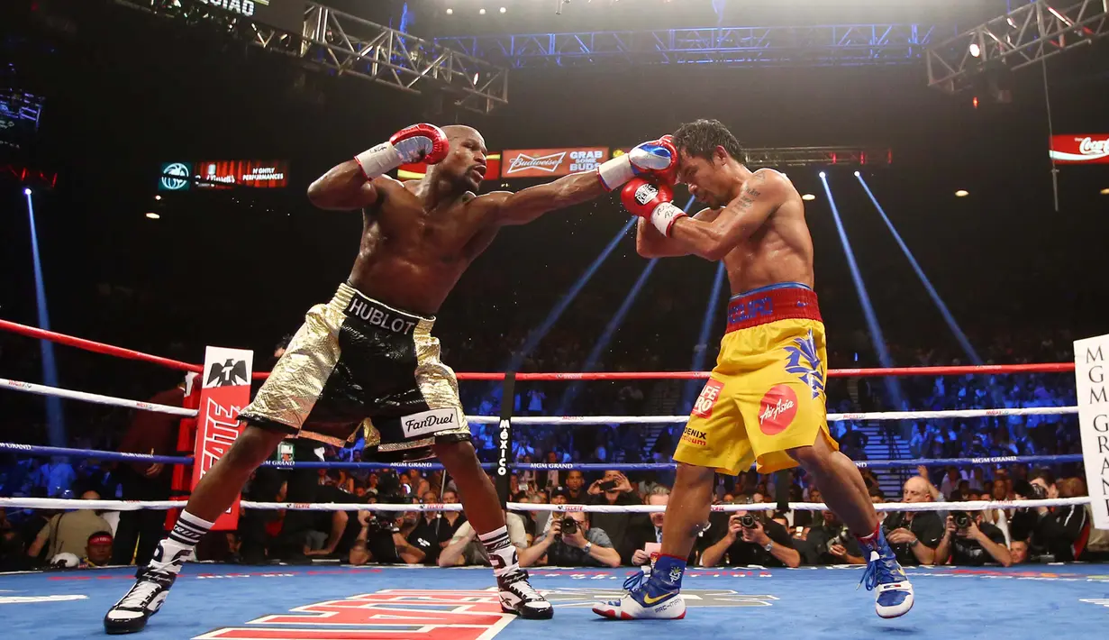 Floyd Mayweather Jr (kiri) berusaha memukul wajah Manny Pacquiao saat pertandingan kelas welterweight di MGM Grand Garden Arena, Las Vegas, Nevada, Minggu (3/5/2015). Floyd Mayweather berhasil manang angka atas Manny Pacquiao. (Mark J. Rebilas-USA TODAY)