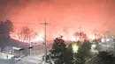 Kebakaran hutan yang melanda di dekat sebuah kota di Sokcho, Korea Selatan (4/4). Dilaporkan api menyebar dengan cepat melalui pegunungan karena angin kencang, membakar sekitar 250 hektar (1 mil persegi) hutan. (AFP Photo/South Korea Out)