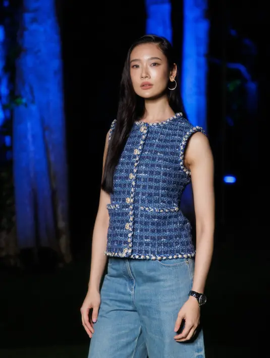Chutimon Chuengcharoensukying mengenakan atasan sleeveless biru dipadukan celana panjang denim. Sambil mengenakan jam tangan hitamnya.