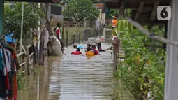 Anak-anak bermain saat banjir merendam Desa Karangligar, Kecamatan Telukjambe Barat, Karawang, Jawa Barat, Kamis (10/2/2021).  Banjir di Desa Karangligar akibat meluapnya sungai Citarum dan Cibeet membuat ratusan rumah terendam banjir dan ratusan hektar sawah. (Liputan6.com/Herman Zakharia)