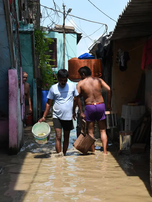 Sejumlah warga mengeluarkan air dari rumah mereka saat banjir melanda perumahan dekat tepi Sungai Yamuna yang meluap di New Delhi, India, Selasa (20/8/2019). (AFP Photo/Sajjad Hussain)
