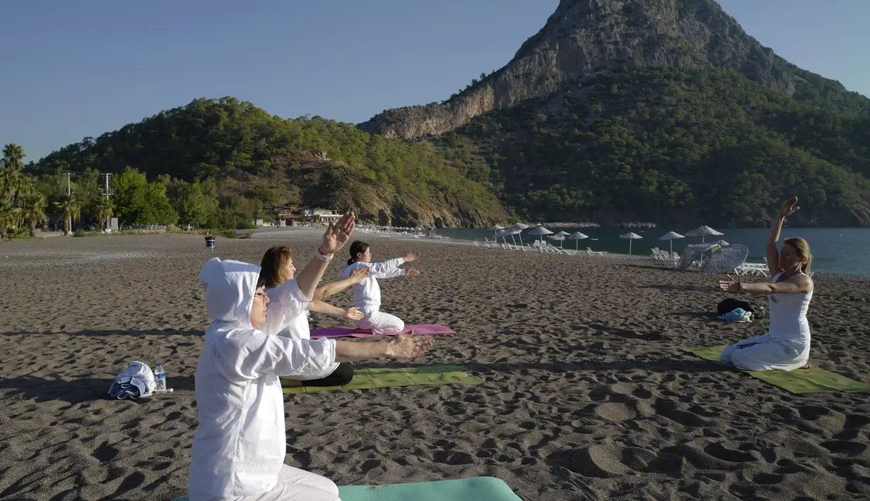 Orang-orang berlatih yoga di pantai di Adrasan, barat Antalya, Turki (24/9/2021). Orang-orang menikmati cuaca hangat di wilayah Mediterania saat salju pertama menyelimuti pegunungan tinggi di timur laut Turki. (AP Photo/Burhan Ozbilici)