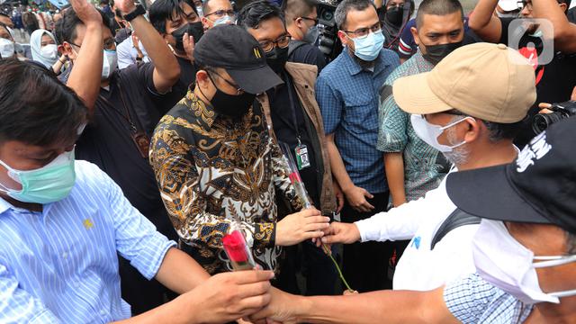 Mantan wakil ketua KPK Bambang Widjojanto memberikan bunga ke Novel Baswedan di luar Gedung KPK, Jakarta, Kamis (30/9/2021). 57 + 1 pegawai KPK yang tak lolos TWK untuk alih status ASN diberhentikan dengan hormat per 30 September 2021. (Liputan6.com/Herman Zakharia)