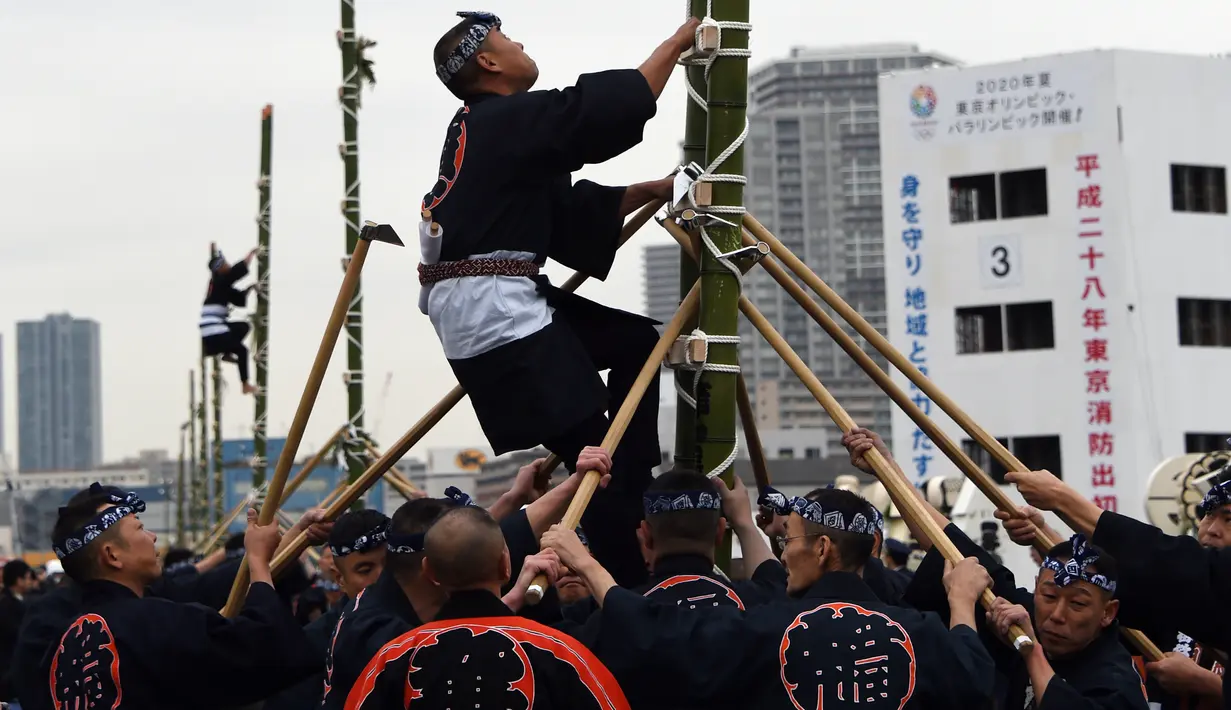 Seorang pemadam kebakaran memanjat tangga bambu setinggi 10 meter saat perayaan Tahun Baru di Tokyo, Jepang, Jumat (6/1). Mereka memperlihatkan berbagai aksi-aksi mendebarkan di atas bambu. (Toshifumi KITAMURA/AFP)