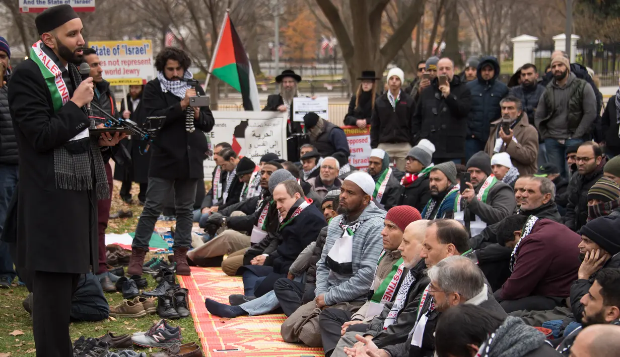 Warga Muslim mendengarkan ceramah saat menggelar Salat Jumat berjamaah di depan Gedung Putih, Jumat (8/12). Para warga muslim ini menggelar sajadah mereka di sebuah taman yang ada di depan kediaman resmi Presiden AS Donald Trump. (mari matsuri / AFP)