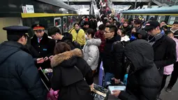 Calon penumpang antre untuk menaiki kereta di sebuah stasiun di Fuyang, Provinsi Anhui, China, Minggu (10/2). Jutaan warga China mulai kembali bekerja setelah menghabiskan liburan Tahun Baru Imlek di kampung halaman. (Chinatopix via AP)