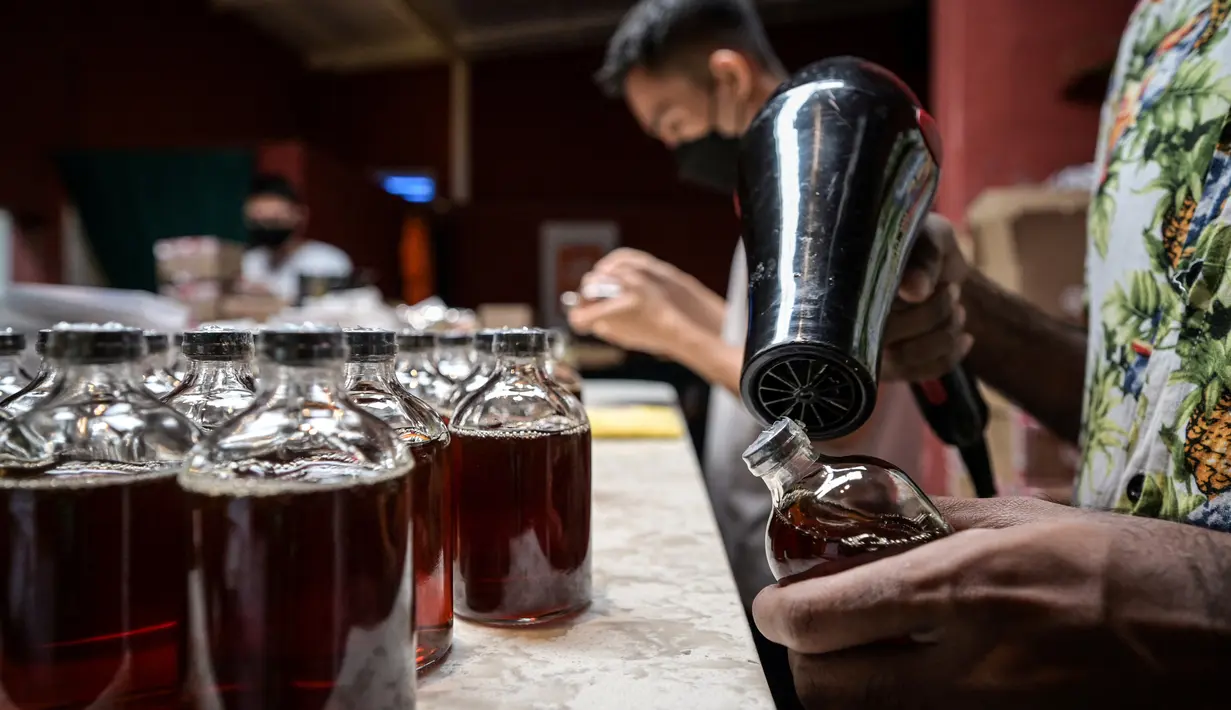 Seorang karyawan menyegel sebotol minuman ExtraGineca, minuman yang terinspirasi oleh vaksin virus corona Covid-19, di sebuah bar koktail di George Town di pulau Penang, Malaysia (8/9/2021). (AFP/Mohd Rasfan)