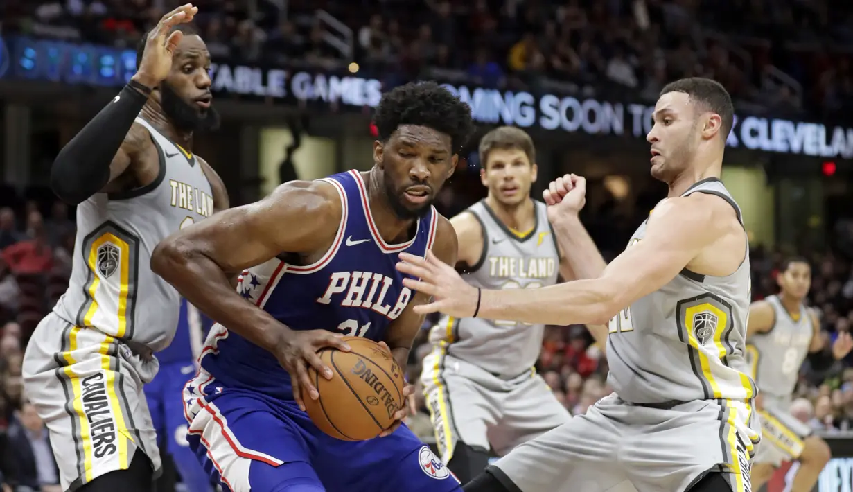 Pemain Philadelphia 76ers, Joel Embiid (tengah) berusaha keluar dari kepungan para pemain Cleveland Cavaliers pada NBA basketball game di Quicken Loans Arena, Cleveland,  (1/2/2018).  Cavs kalah 97-108. (AP /Tony Dejak)