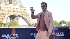 Aktor Hollywood Brad Pitt melambai saat sesi pemotretan untuk film 'Bullet Train' di Paris, Prancis, Sabtu (16/7/2022). Aktor berusia 58 tahun tersebut tampil kasual dengan blazer oranye cerah, celana panjang berwarna serasi, dan T-shirt. (AP Photo/Christophe Ena)
