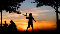 Seorang anak laki-laki bermain dengan pesawat mainan saat matahari terbenam di bukit Kronberg di Hannover, Jerman utara (6/8). (AP Photo/Julian Stratenschulte)