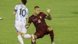 Lionel Messi mendapatkan tekel keras dari bek Venezuela, Luis Martinez. Martinez mengangkat kaki terlalu tinggi saat mencoba merebut bola dari kaki La Pulga.  (Foto: AFP/Miguel Gutierrez, Pool)