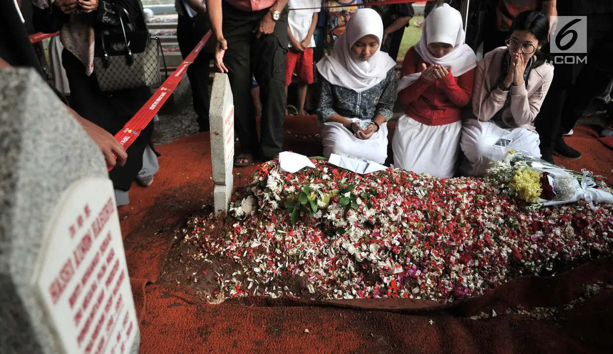 Sejumlah pelajar membaca doa di depan makam Presiden ketiga RI BJ Habibie di TMP Kalibata, Jakarta, Kamis (12/9/2019). Tidak hanya dihadiri tokoh penting, ratusan warga juga antusias datang ke TMP Kalibata untuk mengantarkan BJ Habibie ke tempat peristirahatan terakhirnya (merdeka.com/Iqbal Nugroho)