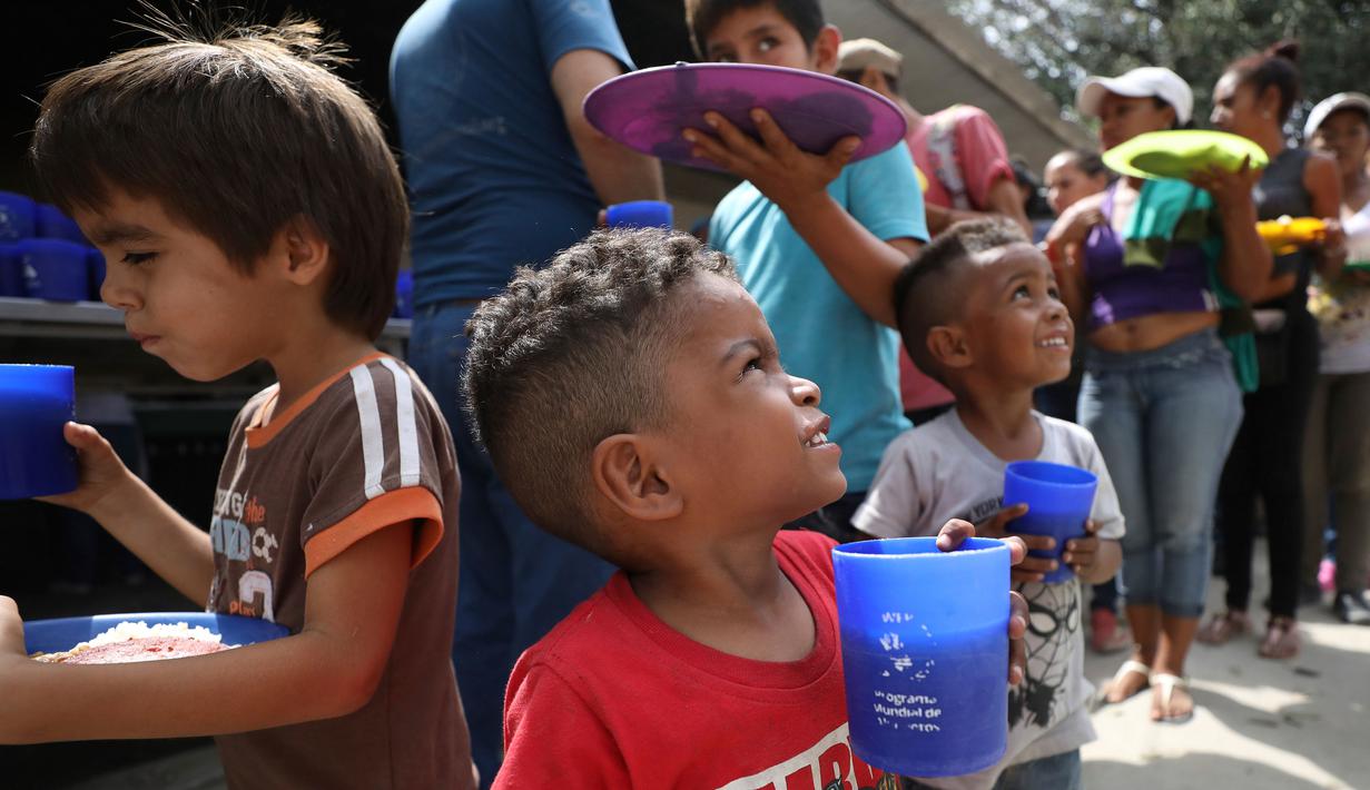 Anak-anak pengungsi Venezuela mengantre makanan di tempat penampungan Divina Providencia, La Parada, Cucuta, Kolombia, Senin (18/2). Makanan terdiri dari kacang-kacangan, daging bologna, nasi, dan sepotong pisang. (AP Photo/Fernando Vergara)