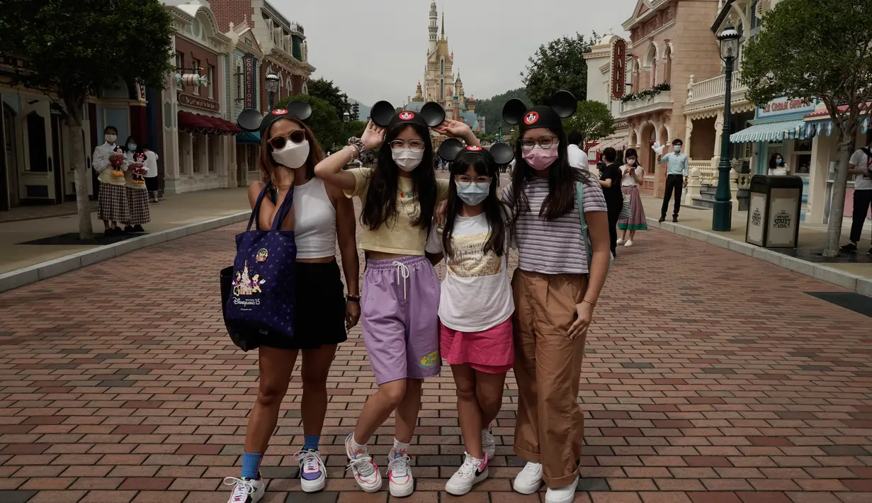 Pengunjung yang mengenakan masker berpose untuk foto di Disneyland Hong Kong pada Jumat (25/9/2020). Setelah dibuka dan tutup kembali, Disneyland Hong Kong dibuka kembali untuk wisatawan. (AP Photo/Kin Cheung)