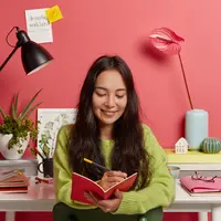 Seorang perempuan sedang mencatat di buku catatannya (Foto Dok: Freepik/freepik).
