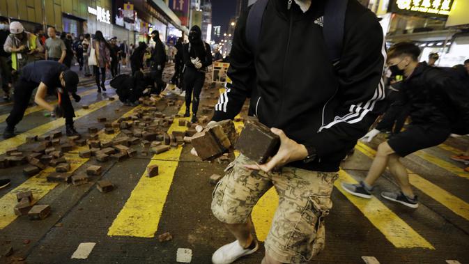Pengunjuk rasa menggunakan mengumpulkan batu untuk mempersenjatai diri selama bentrokan dengan polisi di Mong Kok, Hong Kong (10/11/2019). Ketapel hingga panahan digunakan para demonstran Hong Kong sebagai senjata saat unjuk rasa yang telah berlangsung selama lima bulan. (AP Photo/Dita Alangkara)