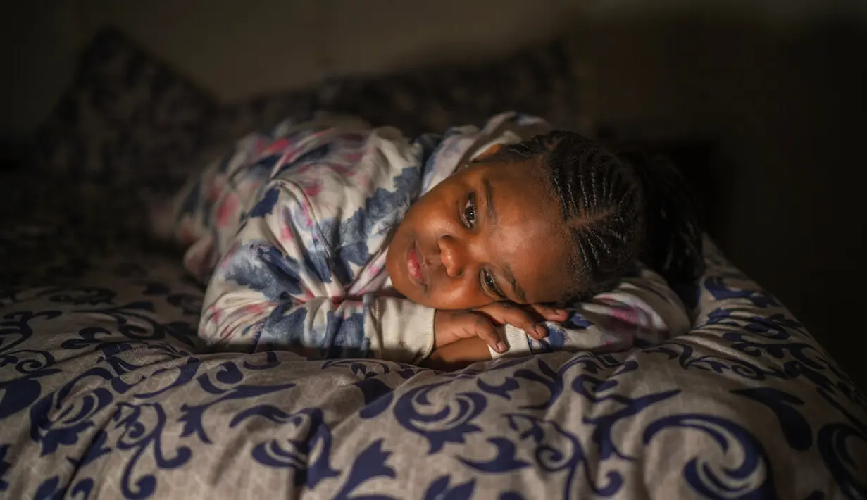 Tshimologo Bonolo (8) berpose di rumahnya di Soweto, Afrika Selatan, pada 26 Juni 2021. Dia kehilangan ayahnya karena COVID-19 pada Juli 2020, dan sekarang dirawat oleh ibu dan neneknya. (AP Photo/Jerome Delay)