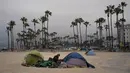 Seorang pria tunawisma memeriksa barang-barangnya di luar tendanya yang dipasang di pantai di lingkungan Venesia Los Angeles, Selasa (29/7/2021). Menjamurnya perkemahan tunawisma di Pantai Venice menimbulkan pertengkaran politik antara para pemimpin Los Angeles. (AP Photo/Jae C.Hong)