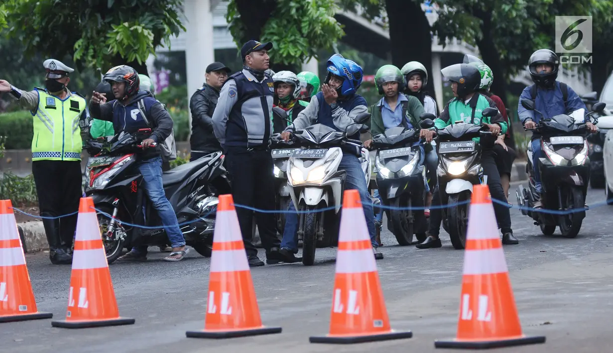 Petugas gabungan mengarahkan pemgendara saat pengalihan arus di Jalan Jenderal Sudirman, Jakarta, Minggu (31/12). Pengalihan terkait malam puncak perayaan pergantian tahun di kawasan Bundaran HI hingga Jalan MH Thamrin. (Liputan6.com/Helmi Fithriansyah)
