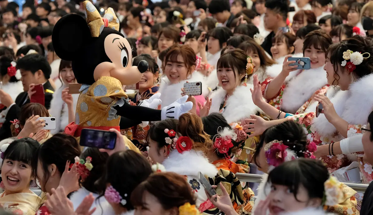 Tokoh Minnie Mouse menyambut para gadis dan pria pada perayaan Coming of Age Day atau Hari Kedewasaan di Tokyo Disneyland, di Urayasu, Senin (13/1/2020). Hari Kedewasaan adalah hari libur umum Jepang yang diadakan setiap hari Senin, minggu kedua di bulan Januari tiap tahunnya. (Kazuhiro NOGI/AFP)