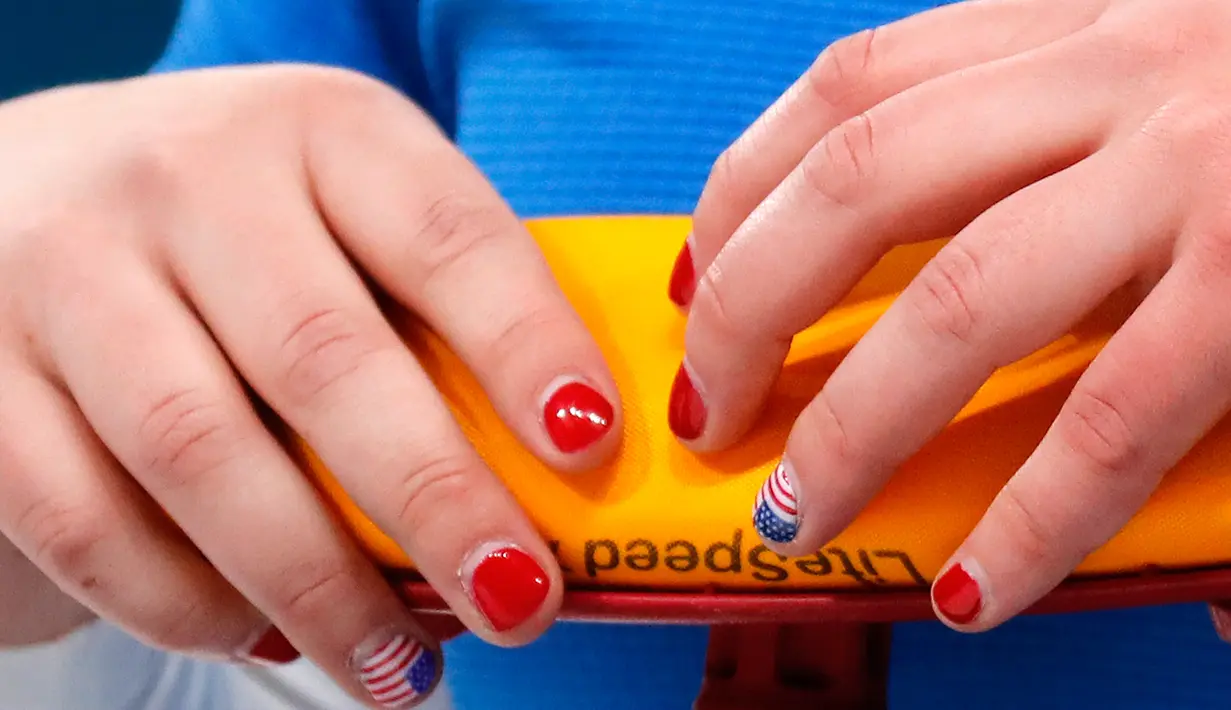 Kuku cantik atlet curling AS, Becca Hamilton yang berhiaskan bendera Amerika terlihat saat dirinya bertanding pada Olimpiade Musim Dingin Pyeongchang 2018, Senin (19/2). Sementara, kuku-kuku lainnya dicat warna merah terang. (AP/Aaron Favila)