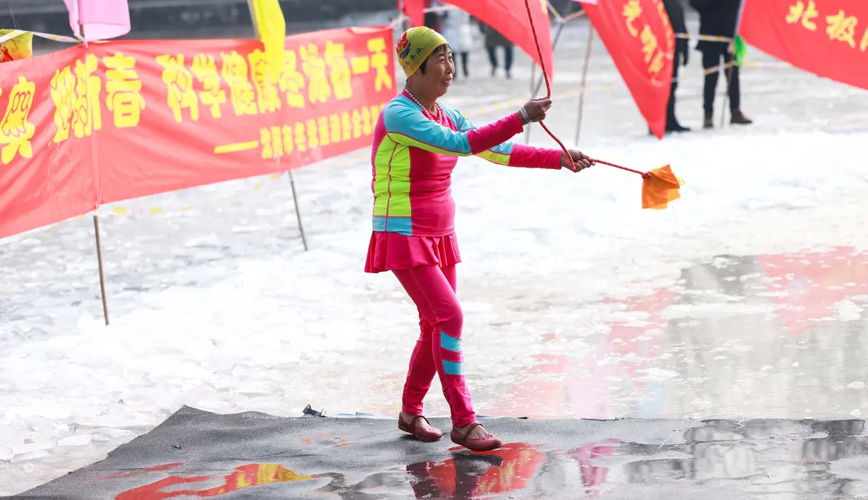 Seorang penggemar renang musim dingin tampil ketika orang-orang berenang di danau yang sebagian beku di Shenyang, di provinsi Liaoning, China pada 25 Januari 2022. Penduduk lokal banyak menggemari kebiasaan berenang di musim dingin di mana banyak sungai dan danau-danau mulai membeku. (STR/AFP)
