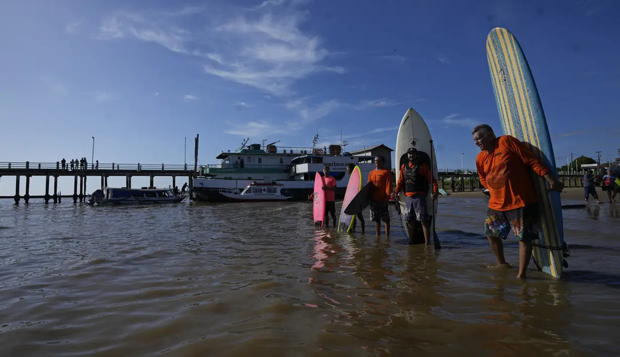 <p>Para peselancar bersiap untuk menaiki gelombang pasang surut yang dikenal sebagai Pororoca saat Festival Selancar Amazon yang diadakan di Canal do Perigoso atau Saluran Berbahaya di muara Sungai Amazon dekat Chaves, Pulau Marajo, Negara Bagian Para, Brasil, Senin (5/6/2023). (AP Photo/Eraldo Peres)</p>