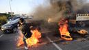 Seorang pengunjuk rasa menendang ban yang dibakar untuk memblokir jalan raya menuju bandara internasional Beirut, Selasa (2/3/2021). Warga Lebanon yang marah memblokir jalan setelah mata uang Lebanon jatuh ke titik terendah baru dalam krisis keuangan yang memicu kemiskinan. (AP Photo/Hussein Malla)