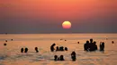 Pengunjung berenang sambil menikmati pemandangan matahari terbenam di Pantai Santa Maria Del Focalo, Pulau Sisilia, Italia, 7 Agustus 2017. Pantai Santa Maria Del Focalo menjadi salah satu tujuan objek wisata favorit di Italia. (ludovic MARIN/AFP)