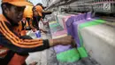 Pasukan oranye atau PPSU menyelesaikan pengecatan warna-warni jembatan layang di kampung Makasar, Jakarta, Kamis (26/7).  Pengecatan dilakukan guna mempercantik dan menyambut Asian Games 2018 pada bulan Agustus mendatang.  (Liputan6.com/Faizal Fanani)