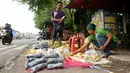 Pedagang jagung dan arang merapihkan dagangannya yang digelar di Jalan Raya Bogor, Depok, Kamis (31/12/2015). Salah satu pedagang mengaku menjual seharga Rp 3.000,- per jagung dan arang Rp 5.000,- per bungkus. (Liputan6.com/Helmi Fithriansyah)