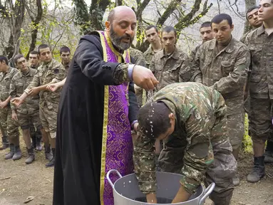 Pendeta Aristakes Hovhannisyan membaptis tentara Armenia di sebuah kamp militer dekat garis depan konflik di wilayah separatis Nagorno-Karabakh, Azerbaijan, Senin (2/11/2020). Pasukan Armenia dan Azerbaijan saling menyalahkan atas serangan baru selama perebutan Nagorno-Karabakh. (AP Photo)