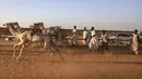 Pemilik unta bersorak saat balapan di trek dekat desa al-Ikhlas, barat kota Omdurman, di Sudan, pada 19 Maret 2021. Perlombaan itu diselenggarakan oleh keluarga suku tradisional yang memelihara unta dari desa setempat untuk melestarikan dan merayakan warisan budaya mereka. (ABDULMONAM EASSA/AFP)
