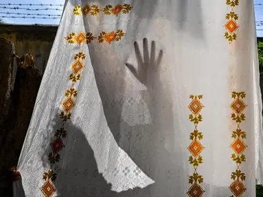 Seorang pekerja mengeringkan kain yang dihias dengan corak batik yang menggunakan teknik pewarnaan dengan menggunakan lilin di sebuah lokakarya di Banda Aceh pada 2 Oktober 2024. (CHAIDEER MAHYUDDIN/AFP)