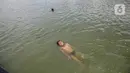 Seorang anak berenang di Danau Sunter, Jakarta, Selasa (2/2/2021). Minimnya lahan bermain anak membuat mereka memanfaatkan tempat yang tidak semestinya untuk bermain karena adanya risiko hanyut dan tenggelam bila tidak mampu untuk berenang. (Liputan6.com/Faizal Fanani)