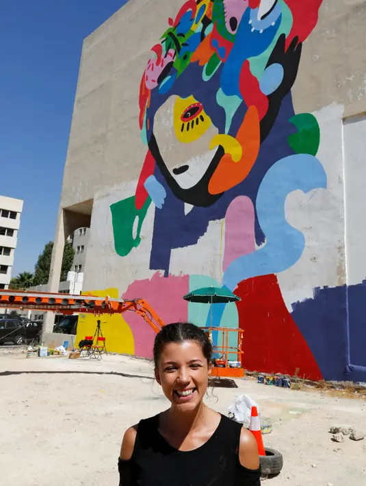 Seniman asal Brasil, Tarsila Schubert tersenyum di depan karya mural yang ia buat di Museum Seni Terbuka, Kota Amman, Yordania, Kamis (29/9). (REUTERS/Muhammad Hamed)