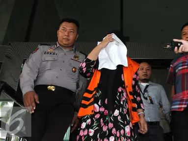 Komisaris CV Timur Alam Raya, Sri Astuti menutupi wajah usai menjalani pemeriksaan di KPK, Jakarta, Senin (22/8). Sri Astuti diduga melakukan penyuapan terkait pengadaan pupuk urea di PT Berdikari tahun anggaran 2010-2012. (Liputan6.com/Helmi Afandi)