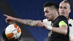 Striker Ajax Amsterdam, Dusan Tadic (kiri) mengontrol bola dibayangi bek AS Roma, Rick Karsdorp dalam laga leg kedua perempatfinal Liga Europa 2020/2021 di Olimpico Stadium, Roma, Kamis (15/4/2021). Ajax bermain imbang 1-1 dengan AS Roma. (AFP/Filippo Monteforte)
