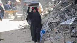 Seorang wanita Palestina membawa barang-barangnya di Khan Yunis di Jalur Gaza selatan pada 6 Maret 2024. Badan Bantuan dan Pekerjaan PBB (UNRWA) menyatakan bahwa rata-rata 63 perempuan terbunuh di Gaza setiap harinya, dan sekitar 37 diantaranya adalah ibu. (Foto: AFP)